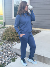Load image into Gallery viewer, Person wearing a blue tracksuit standing outside a house.