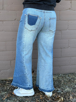 Person wearing blue jeans standing against a brick wall.