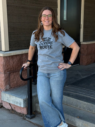 Woman wearing a gray t-shirt with text standing outside a building.