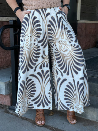 Person wearing a pair of wide-leg pants with a black and white pattern.