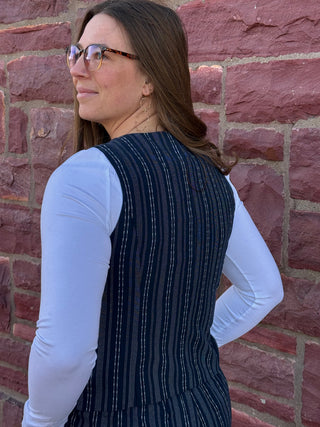 Woman wearing a navy pinstripe dress against a brick wall