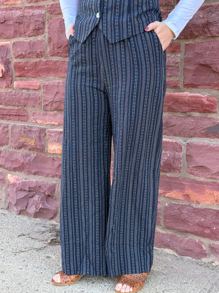 Person wearing a blue striped suit with a brick wall background