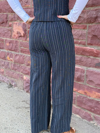 Person wearing a blue striped jumpsuit standing against a brick wall.