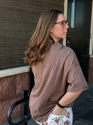 Woman in a brown shirt standing outside a building
