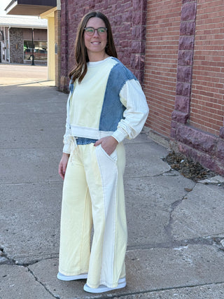 Woman wearing a white and blue outfit standing on a sidewalk next to a brick building.