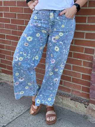 Person wearing blue floral pants standing against a brick wall.