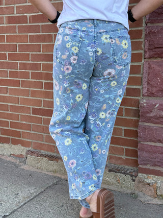 Person wearing blue floral pants standing against a brick wall.