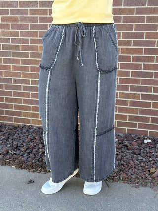 Person wearing wide-leg jeans in front of a brick wall.