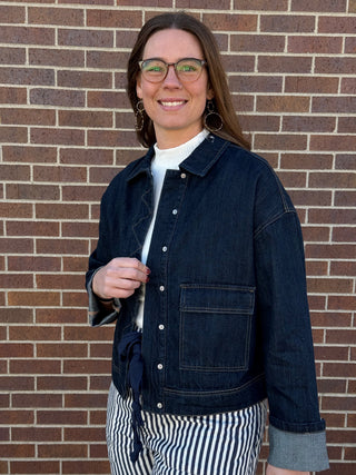 Woman wearing a denim jacket in front of a brick wall