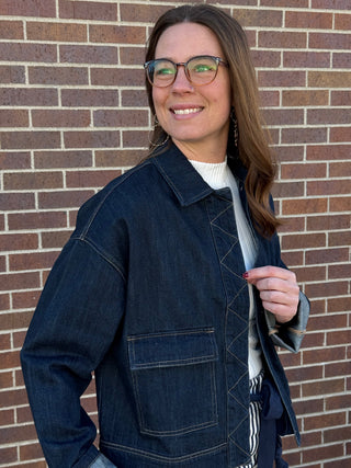 Woman wearing a blue denim jacket in front of a brick wall