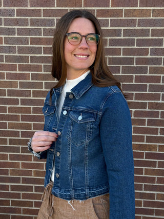 Woman wearing a blue denim jacket standing in front of a brick wall