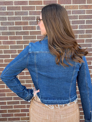 Woman wearing a blue denim jacket in front of a brick wall