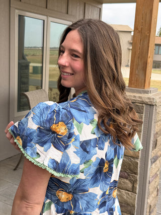 Woman holding a blue floral fabric on a porch