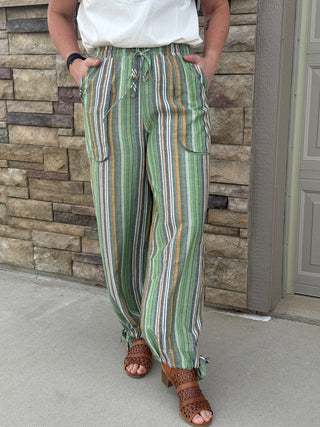 Person wearing green striped pants standing against a stone wall.