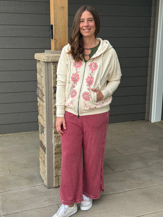 Woman wearing a floral hoodie and pink pants standing on a porch.