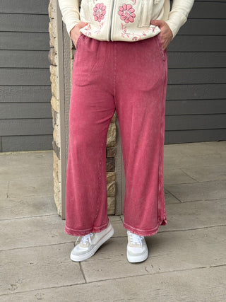 Person wearing pink corduroy pants and a patterned top standing on a wooden deck.