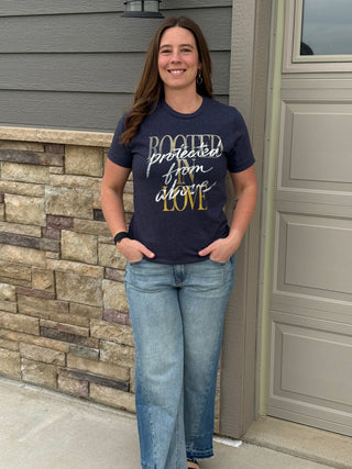 Woman wearing a navy blue t-shirt with text standing in front of a house.