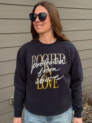 Woman wearing a navy sweatshirt with text standing against a wooden wall.