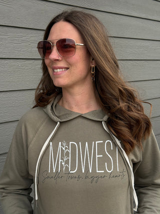 Woman wearing a hoodie with 'Midwest' text against a gray wall