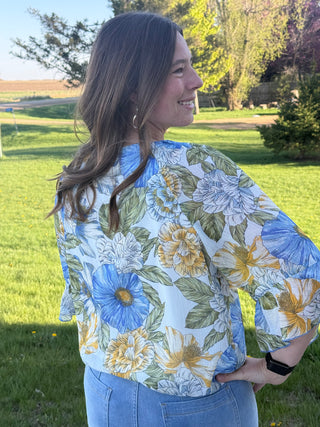 Woman wearing a floral blouse with a park in the background