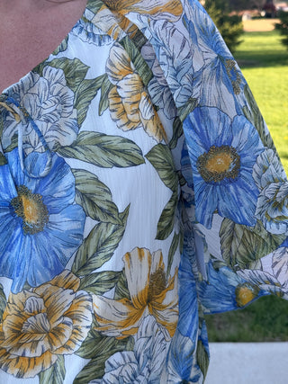 Close-up of a floral-patterned fabric with blue, yellow, and green colors.
