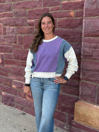 Lady with lavender sweatshirt against a brick wall.
