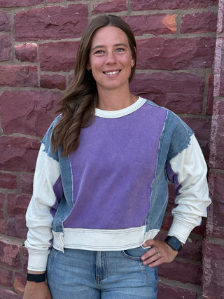 Lady with lavender sweatshirt against a brick wall.