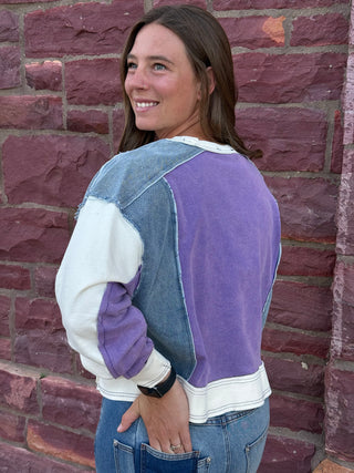 Lady with lavender sweatshirt against a brick wall.