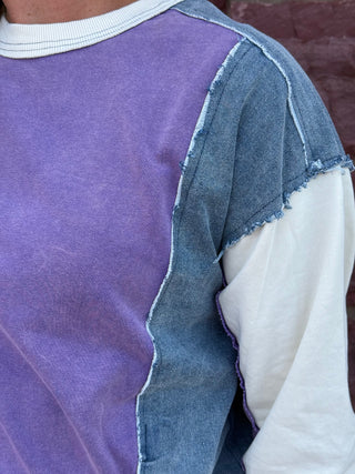 Lady with lavender sweatshirt against a brick wall.