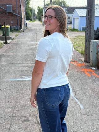 A lady wearing a graphic tee with outdoor scenes. Standing outside.