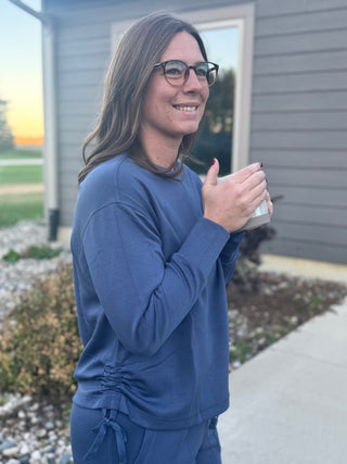 Woman in blue outfit holding a mug outdoors