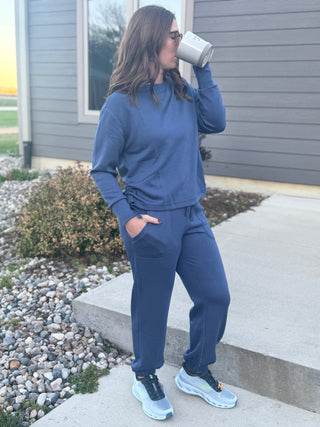 Person wearing a blue tracksuit standing outside a house.