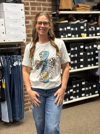 A lady wearing a grey t-shirt with a cross.