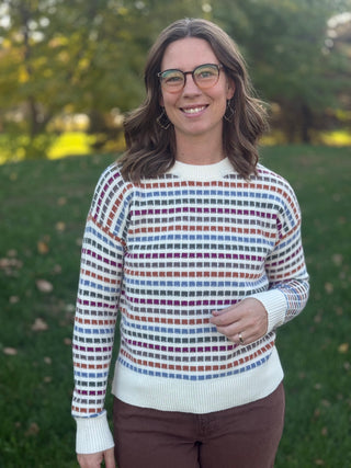 Close-up front view of a multicolor patterned cream sweater with a ribbed crew neckline, cuffs, and hem.