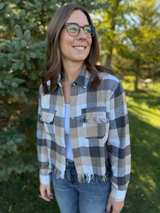 Woman wearing a plaid shirt outdoors with trees in the background