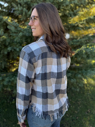 Woman wearing a plaid shirt with a blurred green background