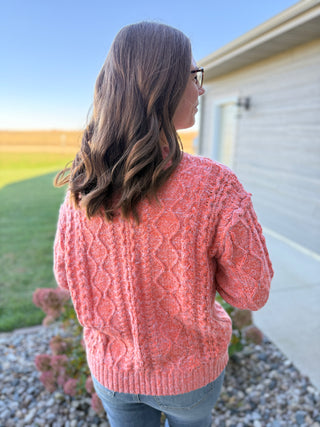 Person wearing a pink sweater standing outside a house