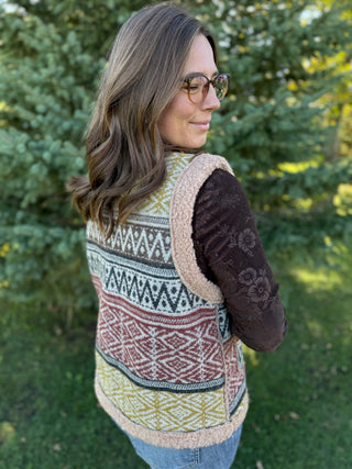 Woman wearing a patterned vest with a blurred green background