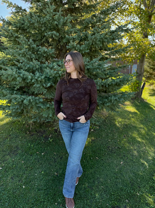 Woman standing outdoors in a grassy area with trees in the background