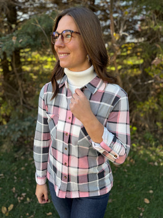 Woman wearing a plaid shirt outdoors with trees in the background