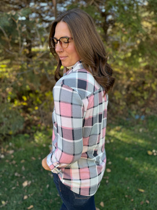 Woman wearing a plaid shirt outdoors with trees in the background