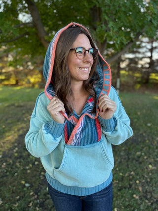 Woman wearing a light blue hoodie with a colorful hood in an outdoor setting