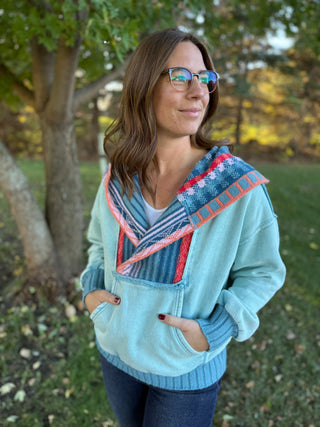 Woman wearing a light blue sweater with colorful patterns outdoors