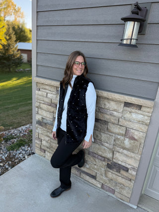 Woman standing against a house exterior with stone and wooden paneling.