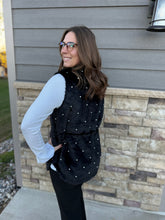 Load image into Gallery viewer, Woman wearing a black pearl accent vest standing against a brick wall.
