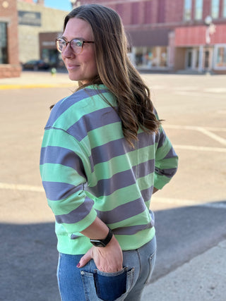 Woman wearing a green and purple striped sweater in an urban setting