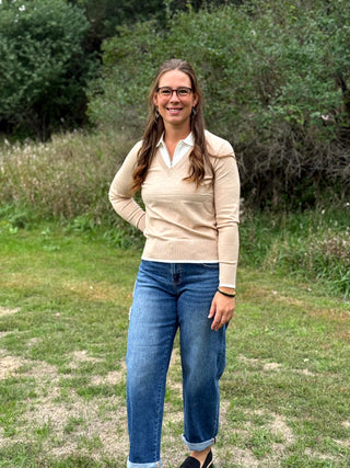 A lady wearing an oatmeal sweater with a 1/4 zip up with ivory trim detail.