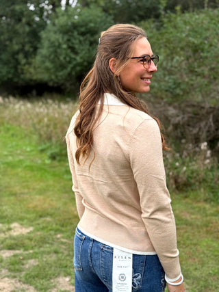 A lady wearing an oatmeal sweater with a 1/4 zip up with ivory trim detail.