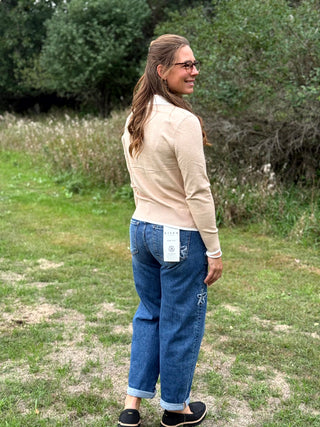 A lady wearing an oatmeal sweater with a 1/4 zip up with ivory trim detail.