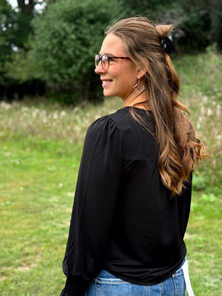 A lady wearing a black top with smocking detail.